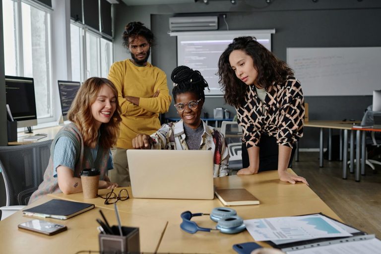 Diverse Group of Office Workers Looking Through Information on Laptop Display