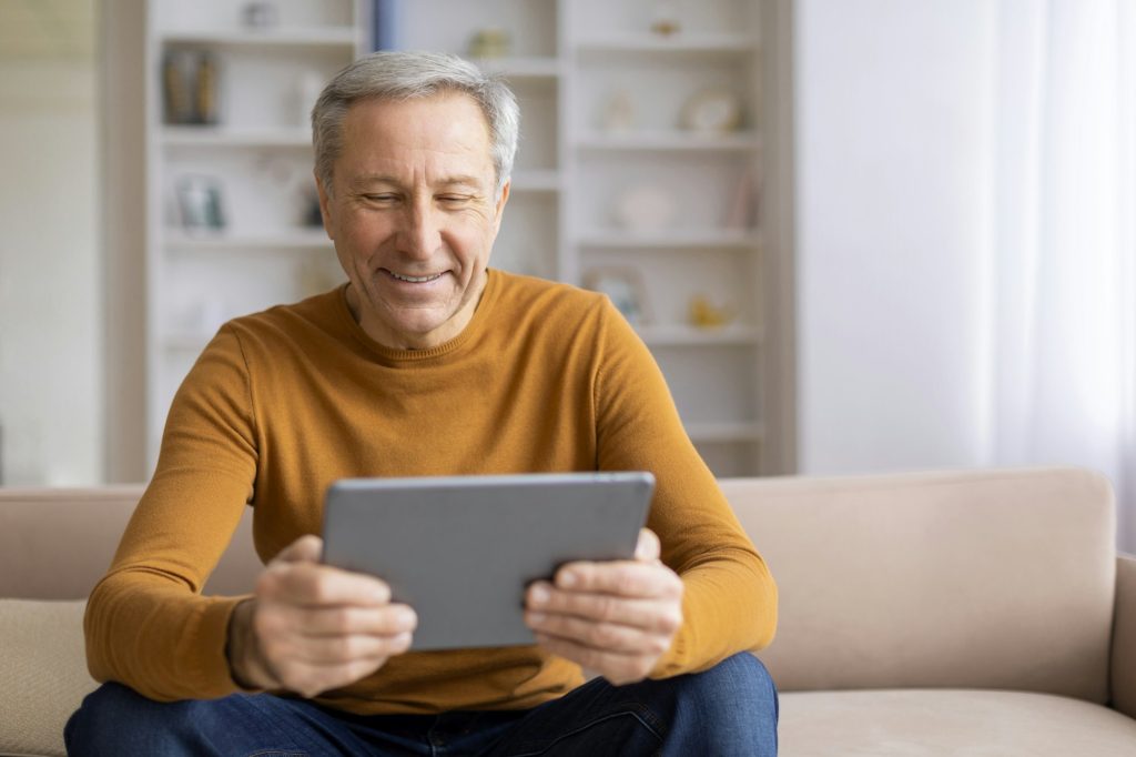 Elderly man reading on a tablet comfortably