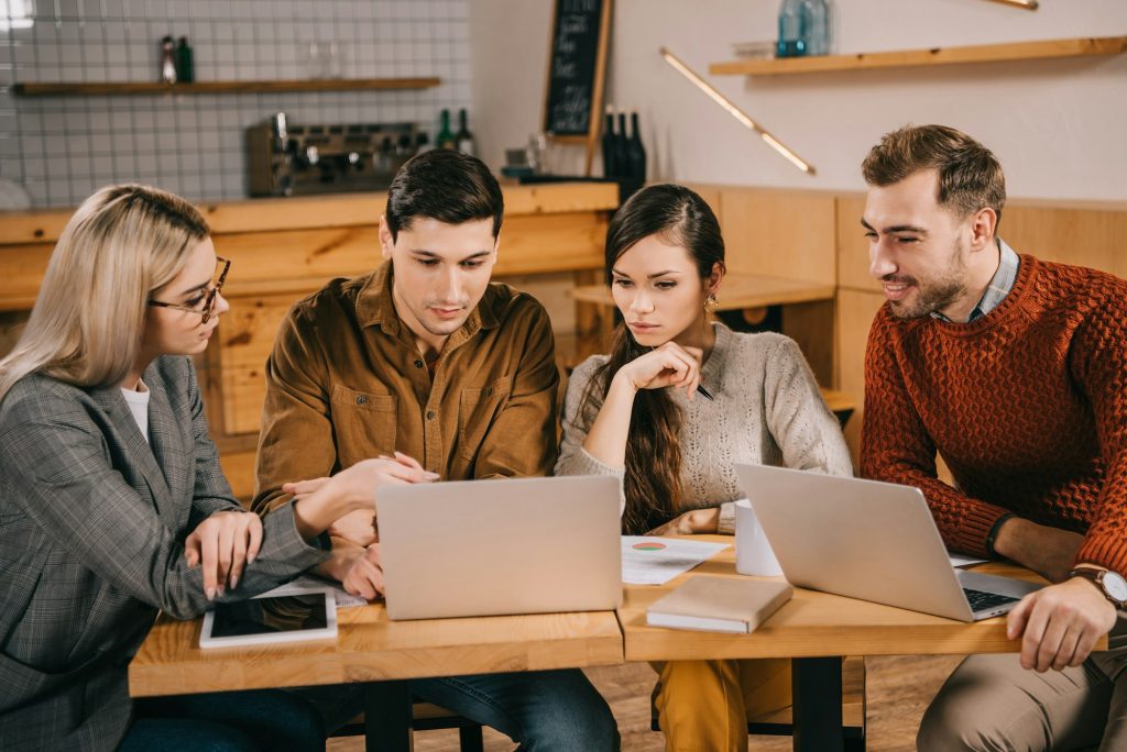 group of colleagues looking at laptop while working in cafe