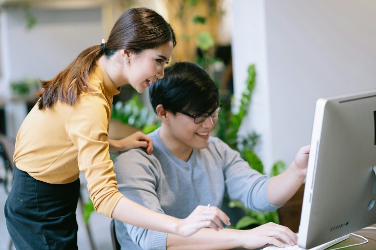 Young Asian businesswoman looking at computer monitor discussing marketing online results project.