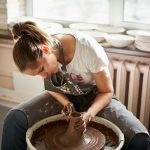 Beautiful woman making ceramic pottery on wheel, hands close-up. Concept for woman in freelance