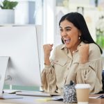Business woman, happy and excited at her office computer, celebration of great news in email. Finan