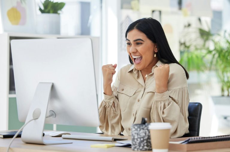Business woman, happy and excited at her office computer, celebration of great news in email. Finan