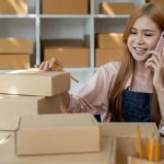 Drop shipping business owner talking on mobile phone and taking order. Female entrepreneur working