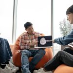 Male holding laptop with AI picture in office with teammates
