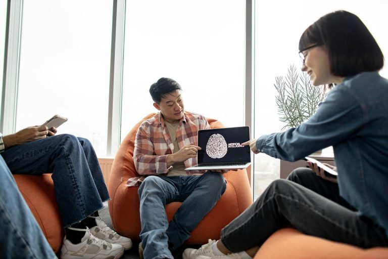Male holding laptop with AI picture in office with teammates