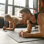 Man and woman standing in plank training at sport club gym