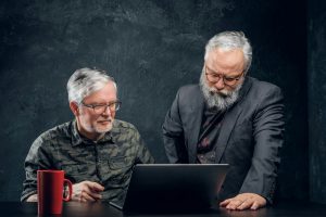 Two elderly businessmen sitting at table with laptop