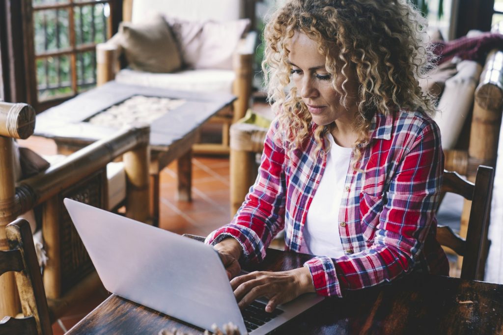 One adult woman at home working on laptop on the table. Modern hipster female people in online job