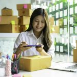 Starting a small business SME owner female entrepreneurs are using a smartphone to take pictures on