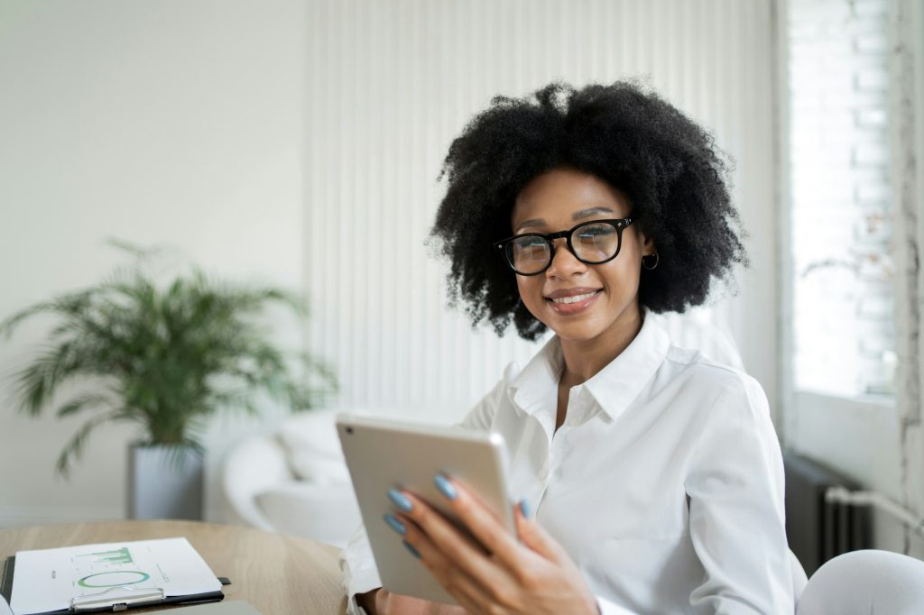 A female secretary makes an online report to the workplace in the office, uses a tablet