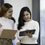 A picture of two Asian business women discussing at a meeting.
