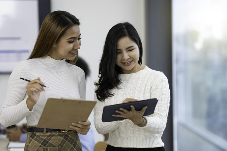 A picture of two Asian business women discussing at a meeting.