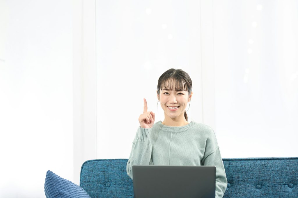 A woman pointing while operating a laptop