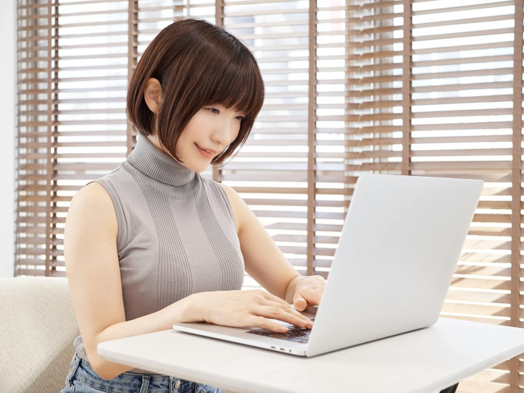 A woman working on a computer in a bright living room