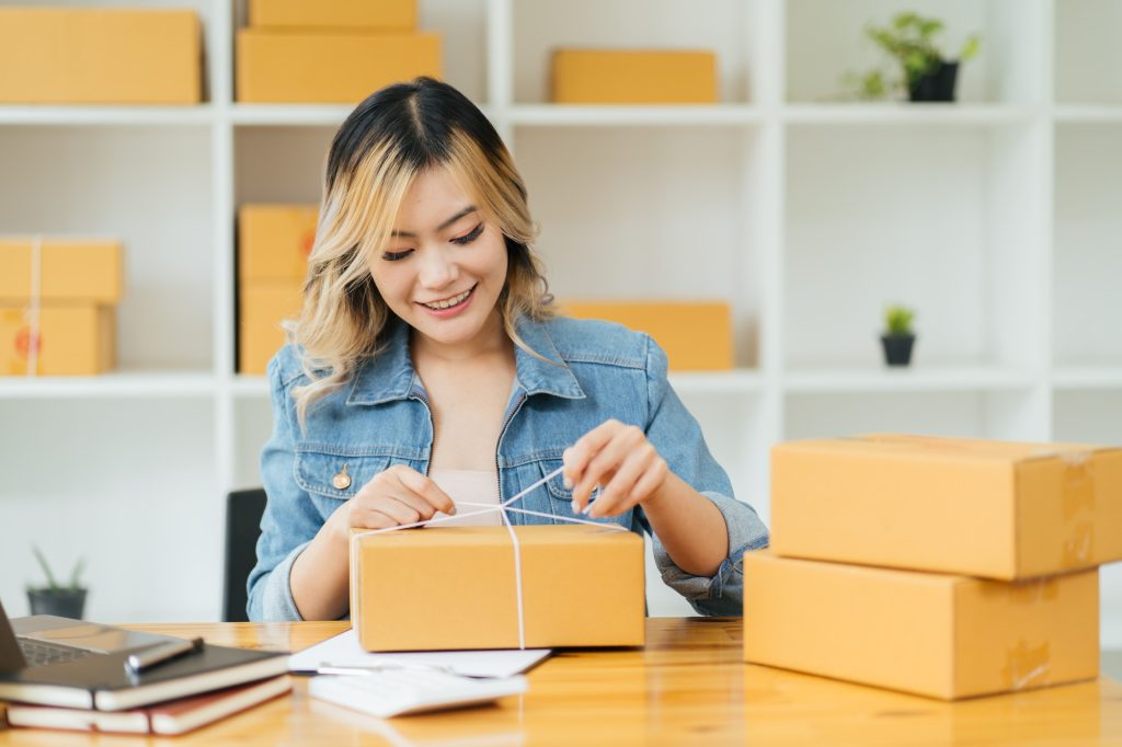 Asian young woman start up small business owner packing in the box at workplace. Online selling, wom