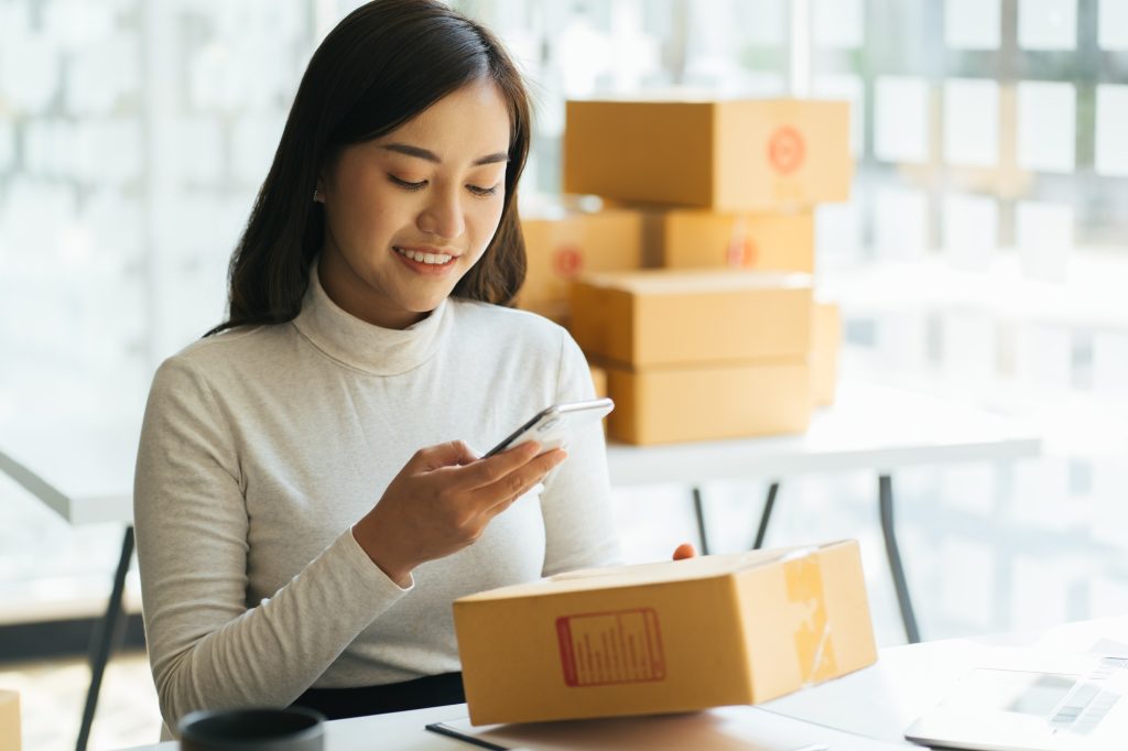 Portrait young attractive asia female owner startup business look at camera work happy with box at h