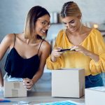 two beautiful freelance business women using smart phone to taking photos to sell online